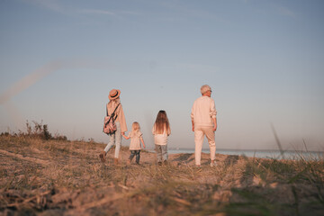 Young mother with daughters and grandmother walk along the shore