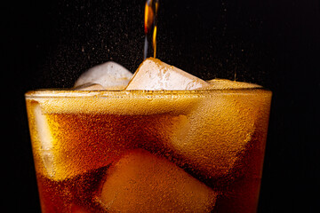 Fizz sparkling cola water refreshing bubbly soda pop with Ice cubes. Glass of cola on black...