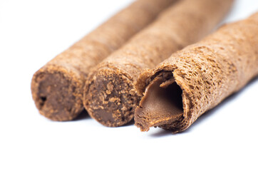 Sweet chocolate waffle rolls stick close up on white background.