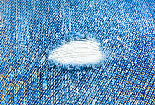 Ripped Blue Hipster Jeans Material. Destroyed Denim Cloth Texture. Close Up.