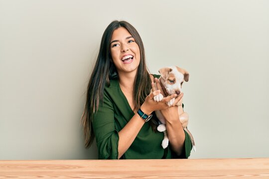 Young hispanic girl smiling happy and hugging dog sitting on the table over isolated white background.