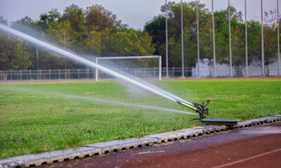 Watering the green grass, blurred background,Automatic sprinkler system watering the lawn,Sprinkler head watering the grass.