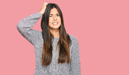 Young brunette woman wearing casual winter sweater confuse and wonder about question. uncertain with doubt, thinking with hand on head. pensive concept.