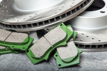 brake pads and perforated brake discs on a stone gray table