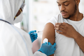 Doctor making flu vaccine for black guy - obrazy, fototapety, plakaty