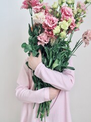 Adorable little girl holding bouquet of flowers. Cute happy child with flower bouquet. Happy Easter. Hello spring banner