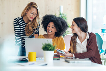 Casual multiethnic business women working with laptops while talking of they new projects together...