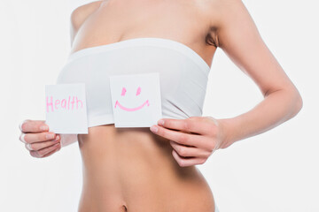 Cropped view of young woman in bra holding cards with health lettering and smile sign isolated on white