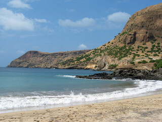 Fototapeta na wymiar Empty beach in Cabo Verde Islands, white sand, surf, blue water and rolling volcanic hills.