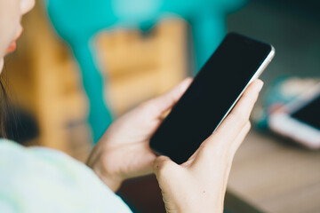Women hand use smartphone with laptop background on table