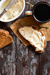 Rustic breakfast. Sandwich with soft cheese and rye bread on a dark wooden background top view. Ricotta sandwich and coffee. Copy space for text. 