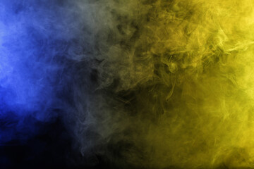 Smoke in blue yellow light on black background in darkness