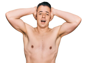 Fototapeta premium Handsome young man wearing swimwear shirtless crazy and scared with hands on head, afraid and surprised of shock with open mouth