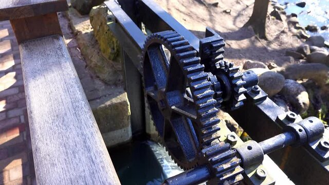 Water Lock Gate Control Gears with Cogwheels On Canal with Waterfall and Rocky Stream underneath on Bright Sunny Morning
