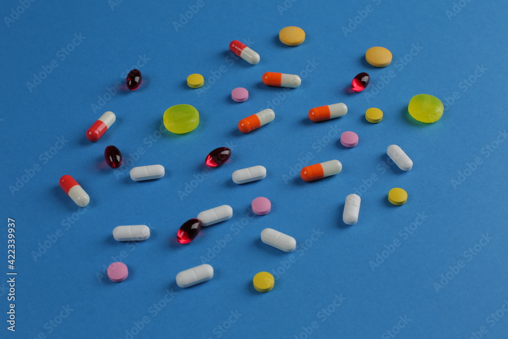 Wall mural Multicolored medical pills of various shapes on a blue background