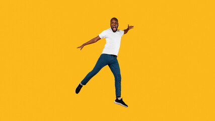 Fototapeta na wymiar African Guy Jumping Shouting Looking At Camera, Yellow Background, Full-Length
