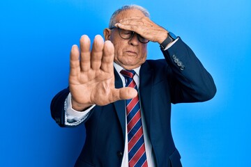 Senior caucasian man wearing business suit and tie covering eyes with hands and doing stop gesture with sad and fear expression. embarrassed and negative concept.