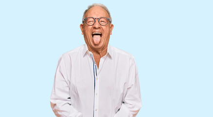Senior caucasian man wearing business shirt and glasses sticking tongue out happy with funny expression. emotion concept.