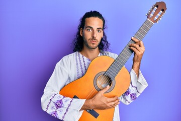 Obraz premium Young handsome man with long hair playing classical guitar depressed and worry for distress, crying angry and afraid. sad expression.