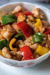 Chicken pieces and bell peppers in a bowl with use of selective focus.