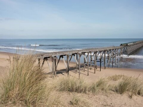Old Abandoned Industrial pier in sandy beach in sunshine. Time lapse
