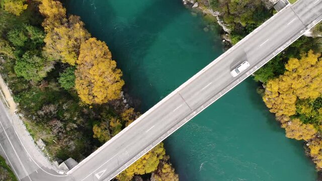 Aerial top down rising shot of cars on the bridge crossing the river, autumn colours.