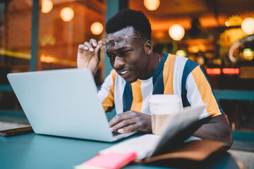 Obraz premium African American male student puzzled on web information received during online education webinar, dark skinned IT professional analyzing program mistake during software developing via laptop