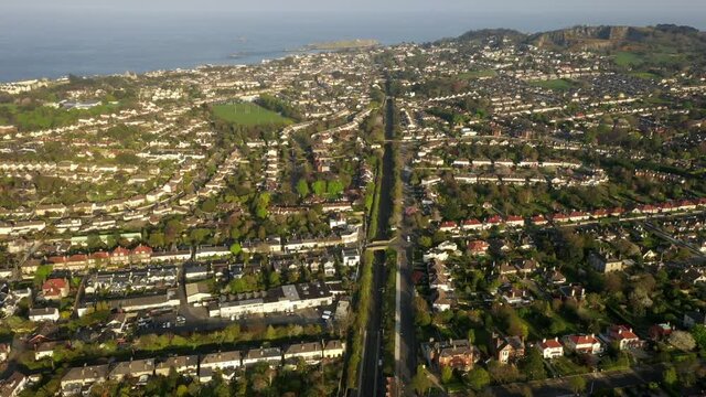 Dun Laoghaire Rathdown, Dublin, Ireland, April 2020. Drone pushes forwards over Glenageary station following Dart line past Albert Road Upper towards Castle Park Road and Dalkey.