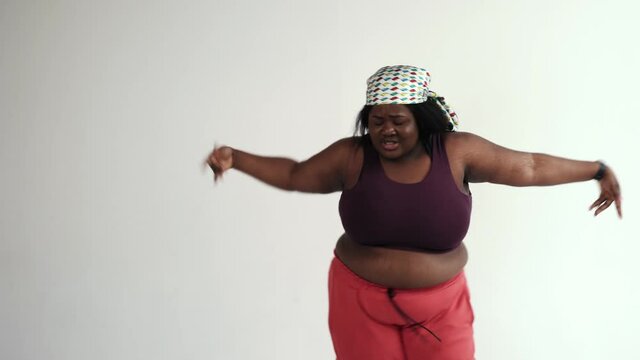Cinematic footage of a young funny woman doing activities on a colored backgound. Doing fitness and dancing at home