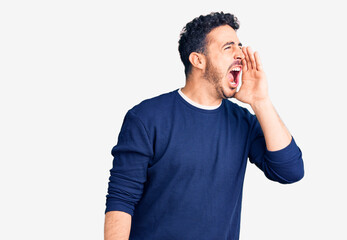 Fototapeta premium Young hispanic man wearing casual clothes shouting and screaming loud to side with hand on mouth. communication concept.