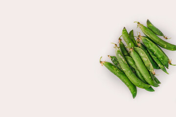 Fresh uncooked peas top view, with copy space against white background. Close up of closed whole green pod containers on a flat surface.
