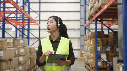 woman staff in reflective vest talking online phone call to help customers solving problem in storeroom with tablet