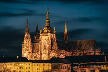 Obraz premium Prague castle during cloudy sunset, lit by surrounding lights