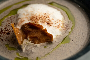 Hot soup with smoked meats in a dark blue plate on a black background close-up.