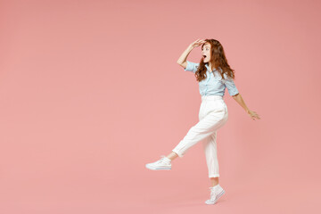 Fototapeta na wymiar Full length young student optimistic smiling happy redhead woman 20s wear blue shirt pants holding hand at forehead looking far away distance isolated on pastel pink color background studio portrait.