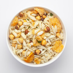 Close-Up of Crunchy Diet Mixture in a white Ceramic bowl made with Puffed Rice, Corn Flakes, and Curry leaves. Indian spicy snacks (Namkeen), Top  View