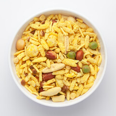 Delicious Khatta Meetha in a white Ceramic bowl, made with peanuts, sugar, raisins, and besan sev. Pile of Indian spicy snacks (Namkeen), Top view