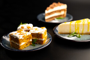 A few different desserts, assorted sweets on plates on a black background. Vanilla classic and chocolate cake, carrot cake.