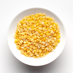 Macro Close up of Organic yellow Gram (Vigna radiata) or split yellow moong dal inside a ceramic white bowl. Top view 