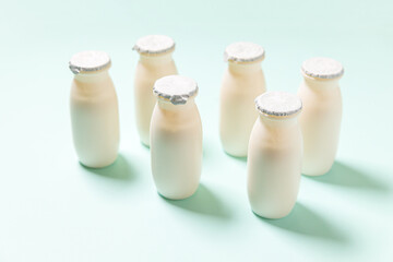 Small bottles with probiotics and prebiotics dairy drink on blue background. Production with...