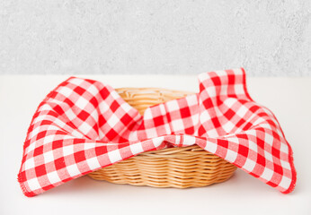 Obraz premium Red checkered tablecloth in a wicker basket on the table