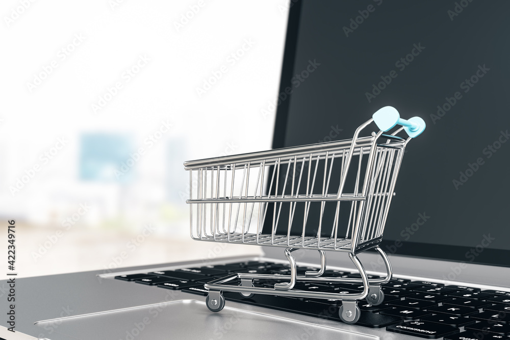 Poster online store and shopping concept with trolley store and opened laptop on abstract background