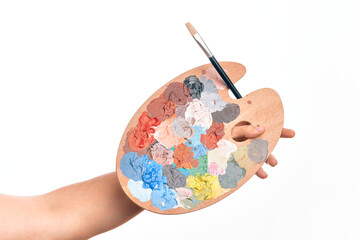 Hand of caucasian young man holding paintbrush and palette with colors over isolated white...