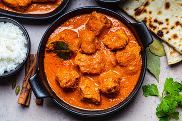 Chicken tikka masala in spicy sauce with rice and chapati bread, dark background, top view, close up. Indian cuisine concept.