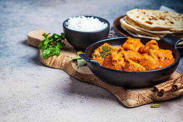 Chicken tikka masala in spicy sauce with rice and chapati bread, dark background, copy space. Indian cuisine concept.