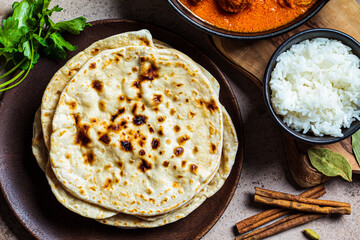 Chapati bread on wooden plate, top view, close up. Indian cuisine concept.