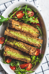 Grilled avocado and cheese sandwiches with fresh salad in white dish, top view. Healthy snack concept.