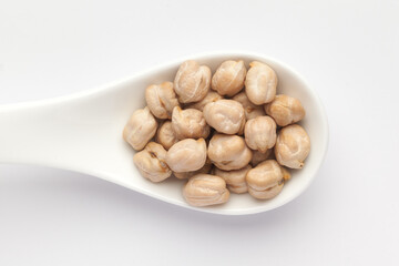 Macro Close-up of Organic chhole chana or Kabuli chana (Cicer arietinum) or whole white Bengal gram dal on a white ceramic soup spoon. Top view