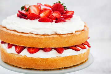 Obraz na płótnie Canvas Victoria`s sponge cake, delicious homemade vanilla cake decorated with whipped cream and fresh strawberries