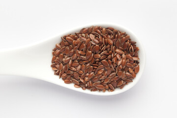 Macro Close up of  Organic Brown flaxseeds (Linum usitatissimum) or linseed on a white ceramic soup spoon. Top view